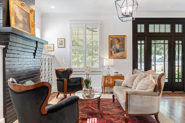 sitting room featuring plenty of natural light, crown molding, wood finished floors, a chandelier, and recessed lighting