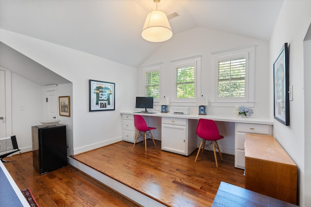 home office featuring built in study area, wood finished floors, and vaulted ceiling