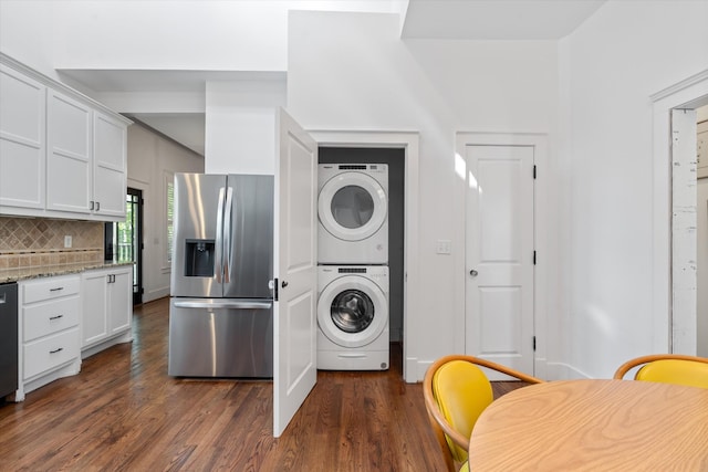 kitchen featuring stainless steel fridge, stacked washer / dryer, dark wood-style flooring, backsplash, and white cabinetry