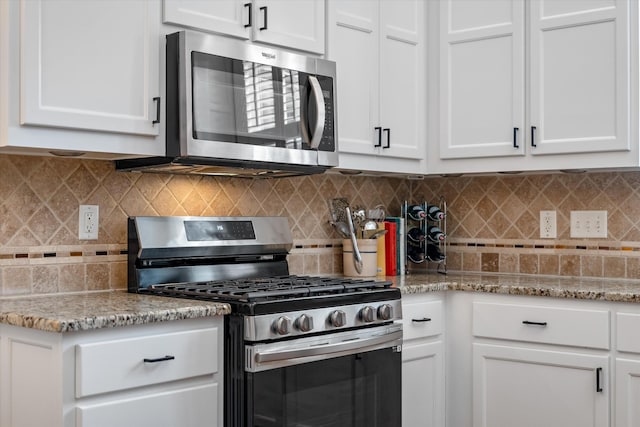 kitchen featuring appliances with stainless steel finishes, white cabinetry, tasteful backsplash, and light stone counters