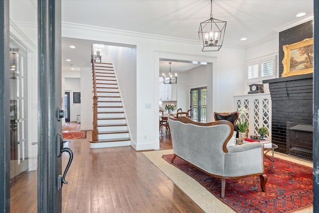 living area with stairs, a chandelier, ornamental molding, wood finished floors, and baseboards