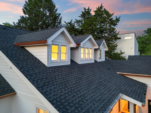 property exterior at dusk featuring a shingled roof