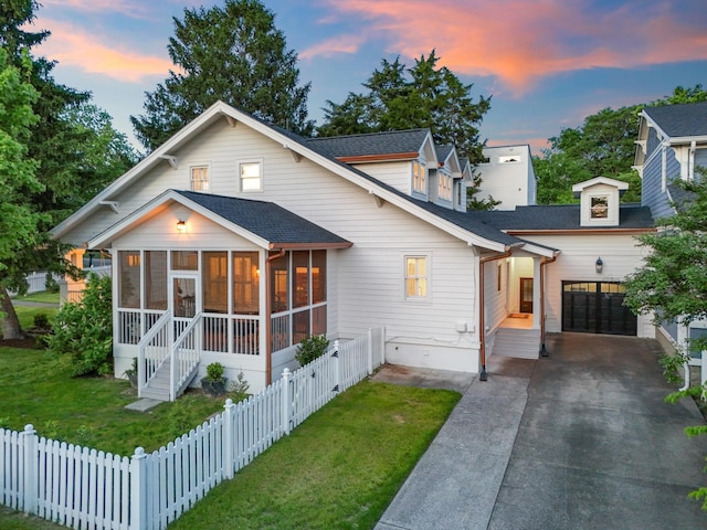 view of front of property featuring a sunroom, roof with shingles, concrete driveway, and an attached garage