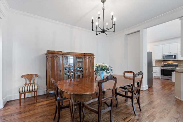 dining space with a chandelier, ornamental molding, wood finished floors, and baseboards