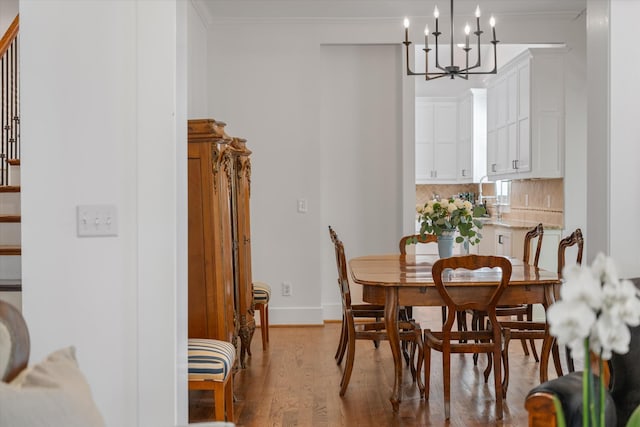 dining room with a chandelier, wood finished floors, crown molding, and baseboards