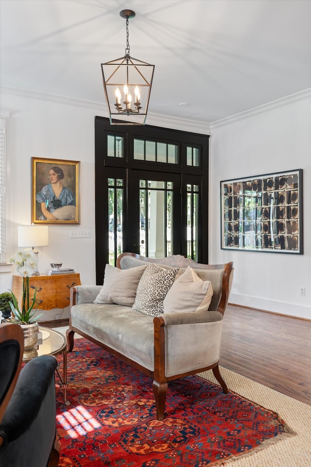 living room with ornamental molding, wood finished floors, a chandelier, and baseboards