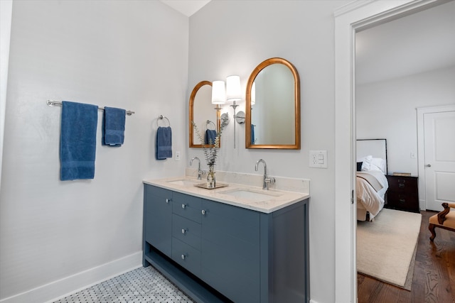 full bath featuring ensuite bathroom, baseboards, and double vanity