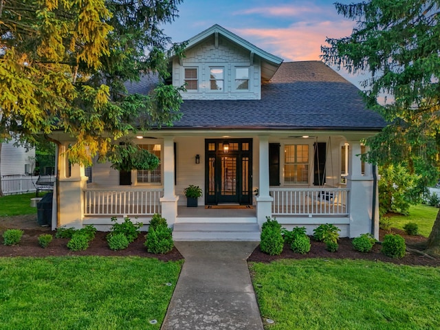 craftsman house featuring a porch, a shingled roof, and a front yard