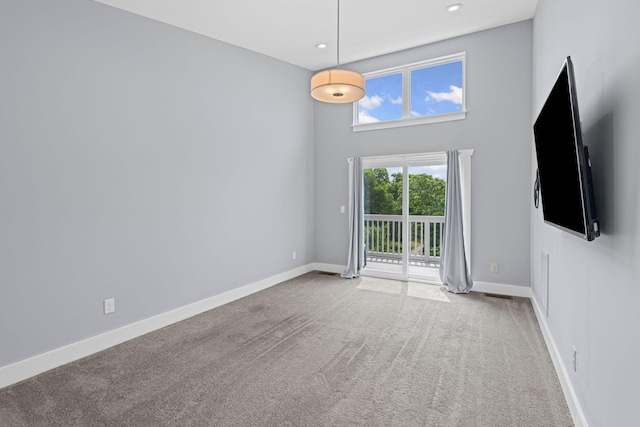 unfurnished room featuring carpet flooring, baseboards, recessed lighting, and a towering ceiling