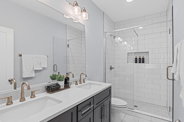 bathroom with a shower stall, double vanity, and toilet