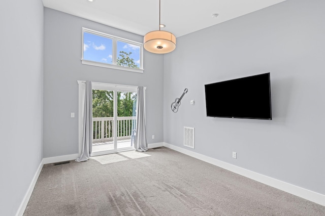 unfurnished living room featuring carpet floors, baseboards, and a high ceiling