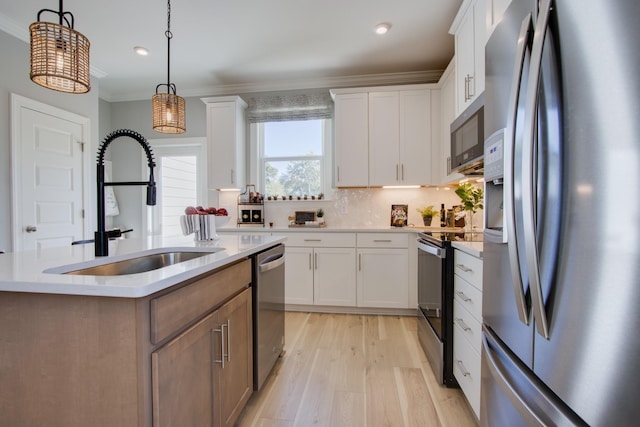 5211 Gladecress Ln, Hermitage, TN 37076 - kitchen featuring stainless steel appliances, a center island with sink, light countertops, light wood-type flooring, and crown molding