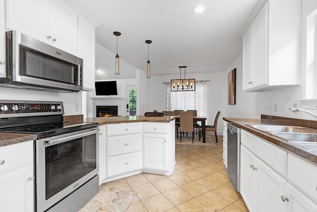 kitchen with appliances with stainless steel finishes, a sink, dark countertops, and white cabinetry