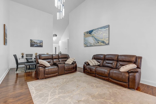 living room featuring a towering ceiling, baseboards, and wood finished floors