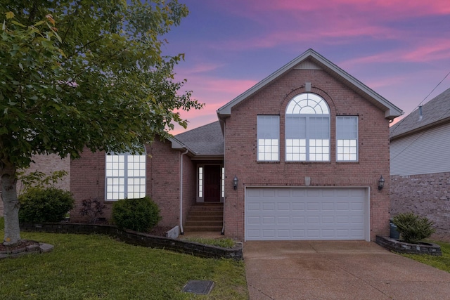 split level home featuring driveway, a lawn, brick siding, and a garage