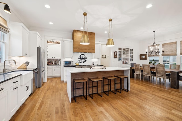 1224 Adams St, Franklin, TN 37064 - kitchen featuring a sink, appliances with stainless steel finishes, a kitchen bar, light wood-style flooring, and decorative backsplash