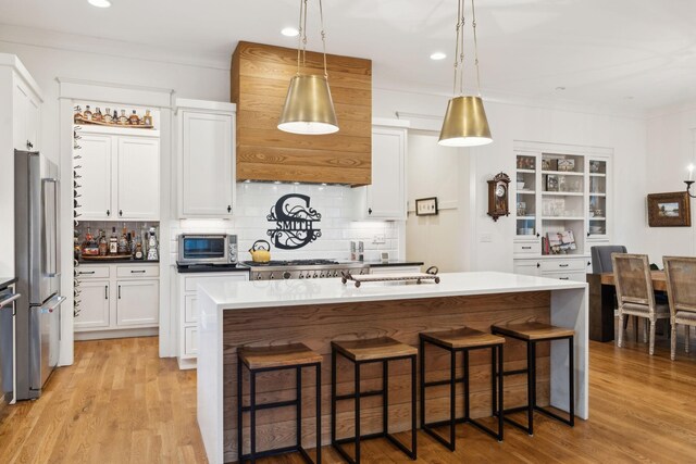 1224 Adams St, Franklin, TN 37064 - kitchen featuring stainless steel appliances, white cabinets, decorative backsplash, light wood finished floors, and a breakfast bar area