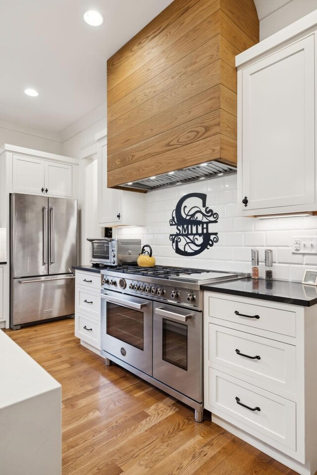 1224 Adams St, Franklin, TN 37064 - kitchen featuring stainless steel appliances, custom range hood, dark countertops, tasteful backsplash, and white cabinets