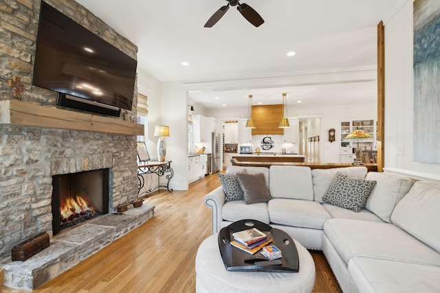 1224 Adams St, Franklin, TN 37064 - living room featuring ceiling fan, a stone fireplace, light wood-style floors, crown molding, and baseboards