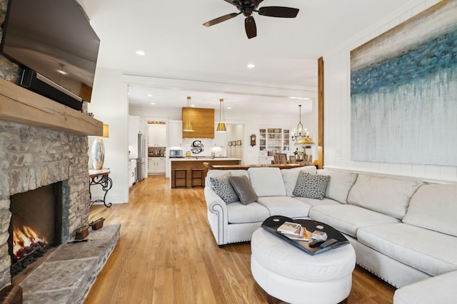 1224 Adams St, Franklin, TN 37064 - living room featuring a ceiling fan, crown molding, light wood-style floors, a fireplace, and a chandelier