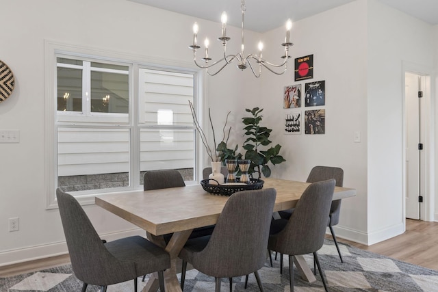 dining space featuring wood finished floors, a chandelier, and baseboards
