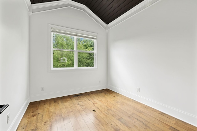 spare room featuring light wood-type flooring, crown molding, vaulted ceiling, and baseboards