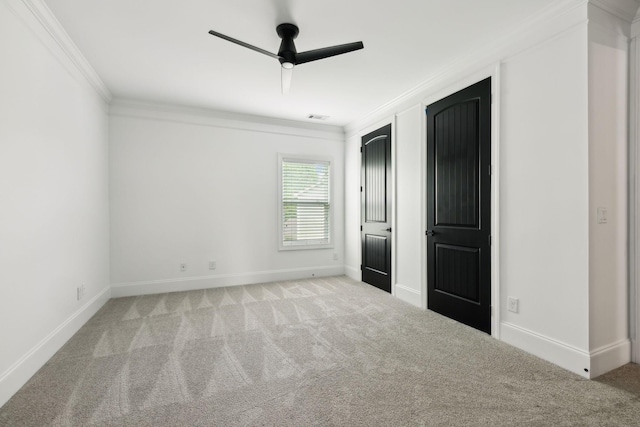unfurnished bedroom featuring crown molding, carpet flooring, baseboards, and a ceiling fan