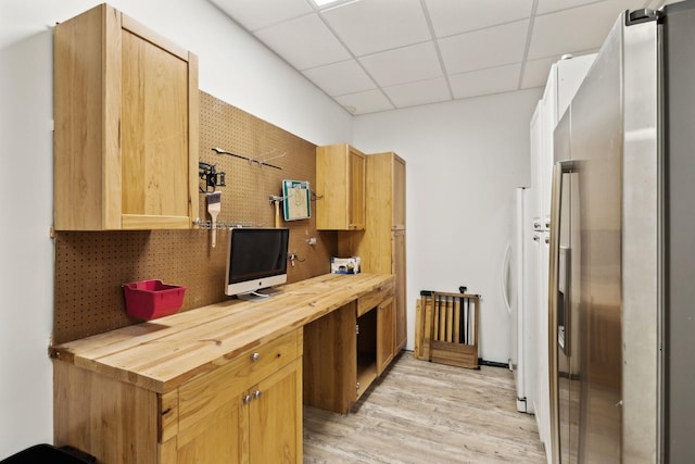 kitchen with stainless steel fridge, wood counters, a paneled ceiling, and light wood-type flooring