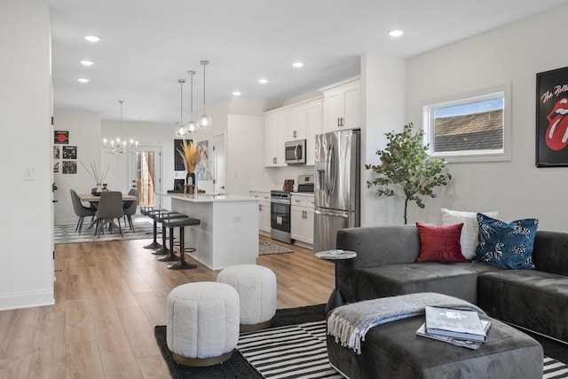 living room with light wood-style floors, plenty of natural light, a chandelier, and recessed lighting