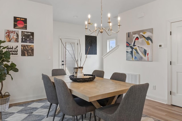 dining area with a chandelier, wood finished floors, and baseboards