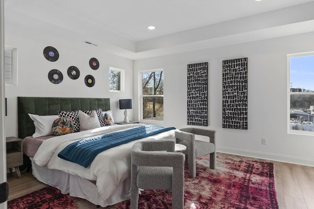 bedroom with wood finished floors, multiple windows, recessed lighting, and baseboards