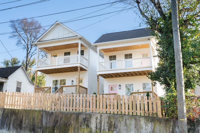 back of house with a balcony and roof with shingles