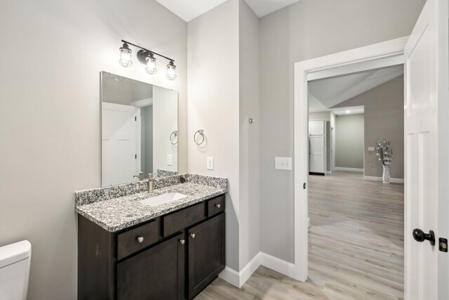 2219 Ovoca Rd, Tullahoma, TN 37388 - bathroom with wood finished floors, toilet, baseboards, vanity, and lofted ceiling