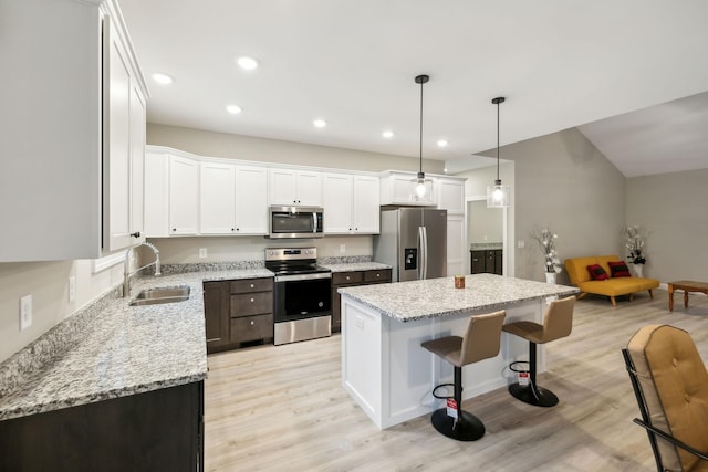 2219 Ovoca Rd, Tullahoma, TN 37388 - kitchen featuring stainless steel appliances, a sink, a breakfast bar area, a kitchen island, and white cabinets