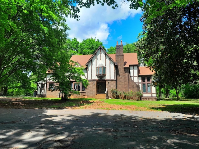 tudor-style house featuring a chimney and stucco siding