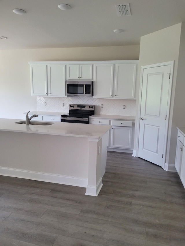 128 Holly Rdg, Antioch, TN 37013 - kitchen with appliances with stainless steel finishes, white cabinetry, backsplash, light countertops, and dark wood-style floors