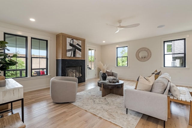 living room featuring baseboards, a fireplace, ceiling fan, light wood-style flooring, and recessed lighting