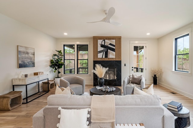living area featuring a fireplace, wood finished floors, recessed lighting, baseboards, and a ceiling fan