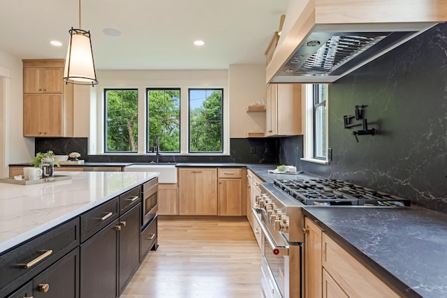 kitchen with appliances with stainless steel finishes, range hood, a sink, light wood-style flooring, and light brown cabinets
