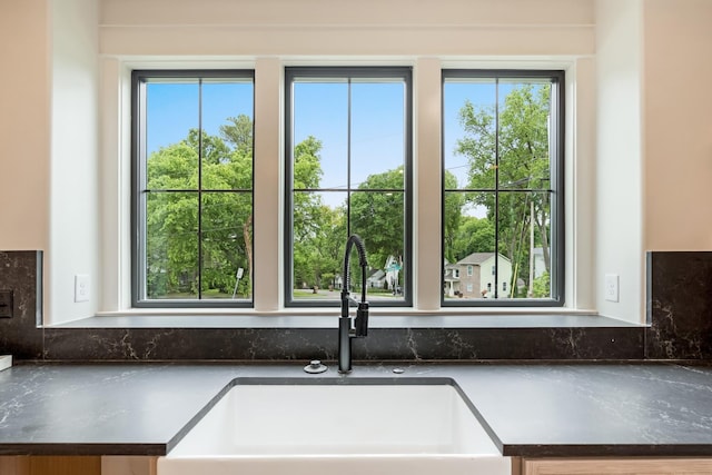 kitchen with a sink, healthy amount of natural light, dark countertops, and tasteful backsplash