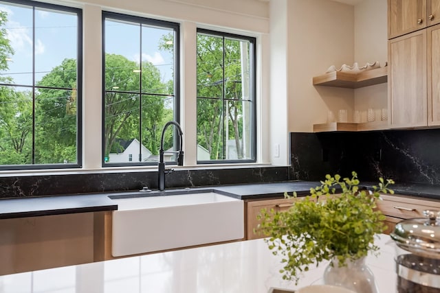 kitchen with open shelves, a sink, dark countertops, and backsplash
