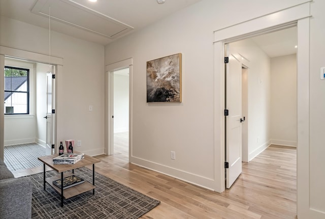 living area with attic access, light wood finished floors, and baseboards