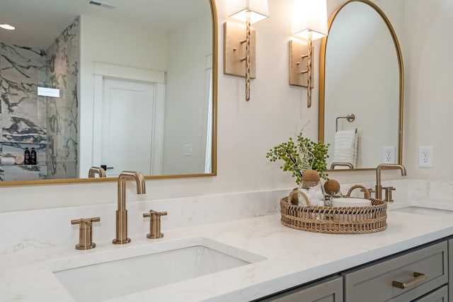 bathroom featuring double vanity and a marble finish shower