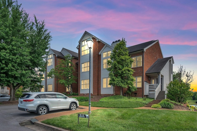 view of front of house featuring brick siding, a front yard, and a chimney