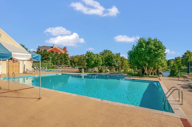 community pool with a patio area and fence