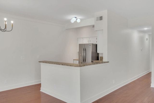 kitchen with freestanding refrigerator, baseboards, white cabinetry, wood finished floors, and a peninsula