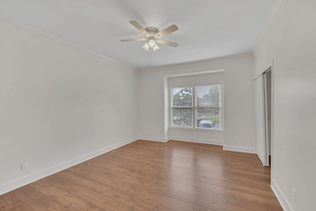 empty room featuring crown molding, ceiling fan, wood finished floors, and baseboards