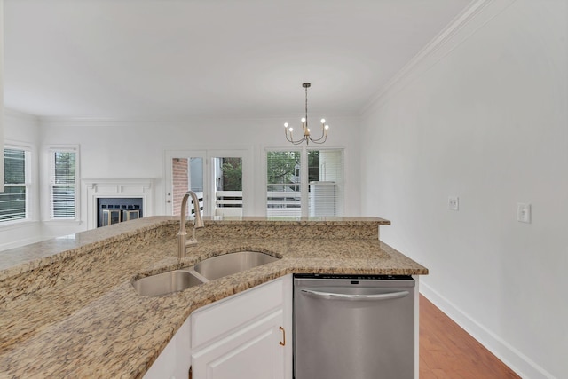 kitchen featuring stainless steel dishwasher, a sink, a chandelier, light stone counters, and healthy amount of natural light