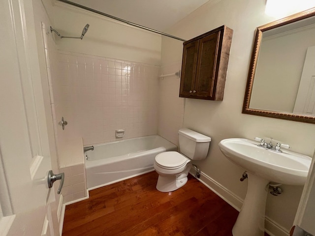 bathroom featuring wood finished floors, toilet, shower / washtub combination, and baseboards