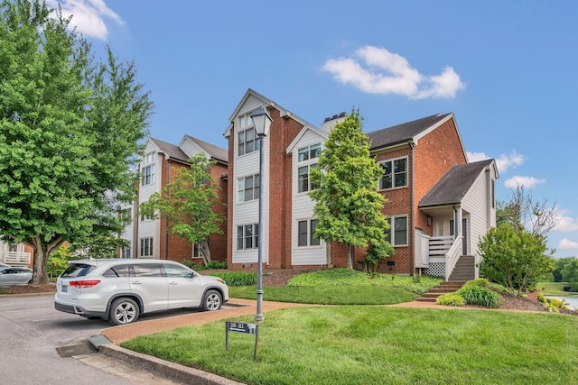 view of front of property featuring a front yard, brick siding, and a chimney